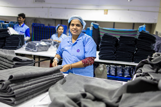 Factory workers organize clothes in an industrial setting.
